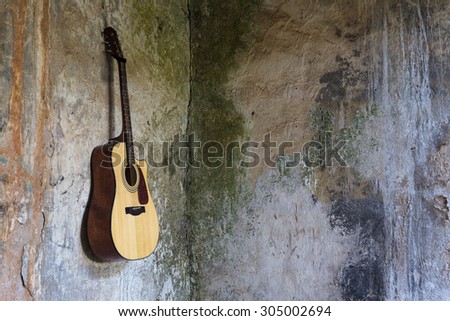 Guitar hanged on the wall in the broken house. Focus put only on guitar and inside part of house.