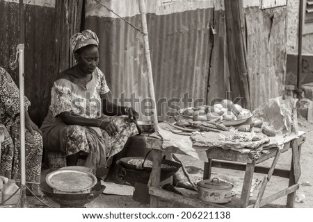Mbour, Senegal - July 9, 2014: A woman selling food on the street roasts peanuts in a wok on July 9, 2014 in Mbour, Senegal.