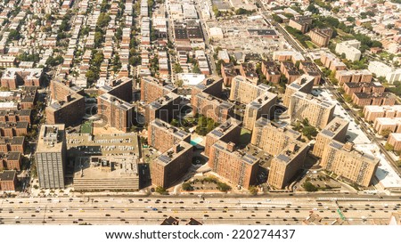 Aerial view of the Borough of Queens, New York, showing geometrically arranged and densely packed buildings and a multi-lane super highway