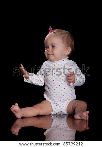 A cute image of a beautiful baby girl with a pink flower bow in her hair.  Image is isolated on black with reflection.