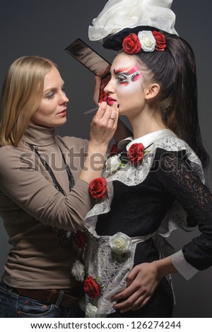 Young model having her makeup done before her shoot, make up master