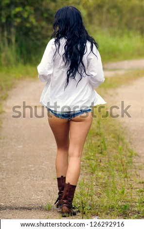 Girl in mini denim shorts walking along countryside road (going out, jeans style)