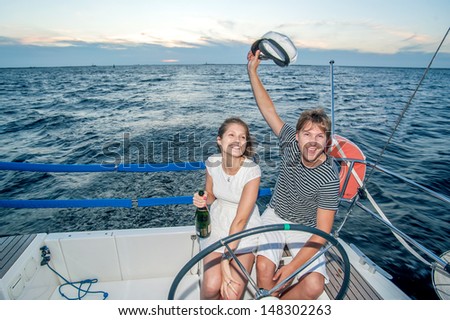 Happy young couple drinking champagne on yacht