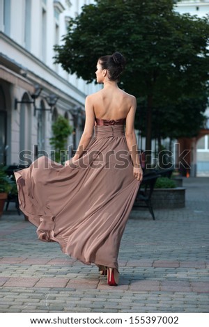 Fashionable girl in brown dress on a city street
