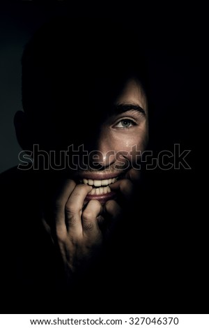 Shocked young man in dark shadow and ray of light