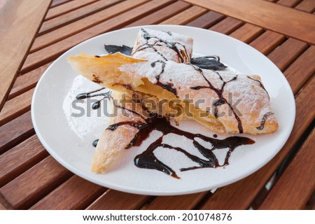 Piece of cherry strudel with chocolate. All sprinkled with powdered sugar.