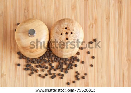 salt and pepper grinders on a table, with pepper spread around