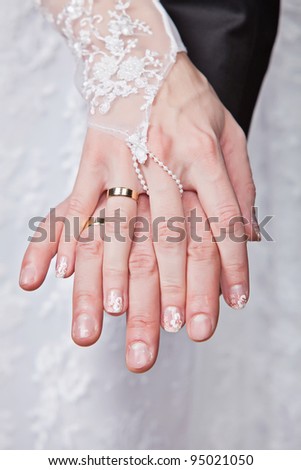 Wedding details - closeup of hands of newly-married with gold rings