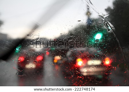 Street in the rain through the window of the car