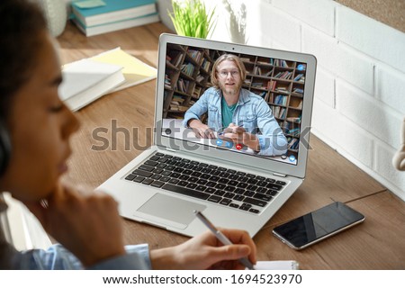 African teen girl college student, school pupil wears headphones distance learning from home on video conference call, web cam chat with online teacher tutor remote lesson on computer screen, closeup.