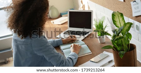 Focused african american teen girl student pupil writing notes in notebook distance learning studying online makes goals check list at home office. Remote college school education, elearning concept.