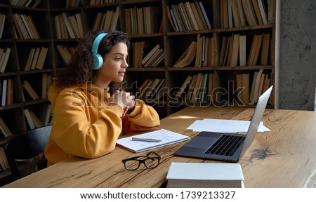 Hispanic teen girl, latin young woman school college student wear headphones learn watching online webinar webcast class looking at laptop elearning distance course or video calling remote teacher.