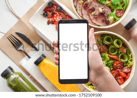 Hand of woman hold phone mock up white screen over weight loss diet fresh healthy food take away boxes bag daily nutrition ready menu plan meal online delivery service mobile app ad. Flat lay top view