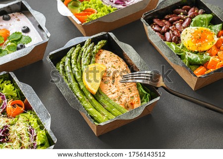 Ready healthy food catering menu in lunch boxes fish and vegetable packages as daily meal diet plan courier delivery with fork isolated on black table background. Take away containers order concept. Сток-фото © 