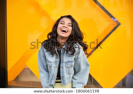 Happy African American woman wearing denim jacket laughing looking at camera standing near city street building. Smiling positive mixed race generation z hipster lady posing outdoor. Zdjęcia stock © 