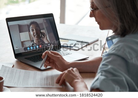 Old hr employer checking indian female job applicant cv resume by video conference call interview on laptop. Senior client reading insurance contract with virtual lawyer advisor at online legal advice