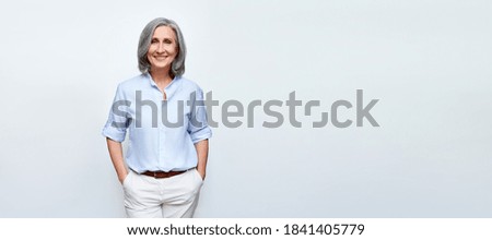 Smiling beautiful mature business woman standing isolated on white background. Older senior businesswoman, 60s grey haired lady professional female ceo, coach looking at camera, banner, copy space.