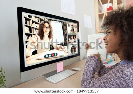 Cute african kid child girl showing homework talking to remote teacher distance learning during virtual online class on video conference call with tutor and school children group at home on computer.