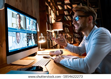 Business man having virtual team meeting on video conference call using computer. Social distance worker working from home office talking to diverse colleagues in remote videoconference online chat.