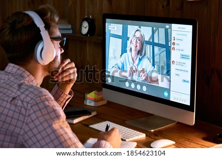 Male student wearing headphones taking online course training, watching webinar, remote seminar university class, virtual learning with social distance web teacher, tutor or coach on computer screen.