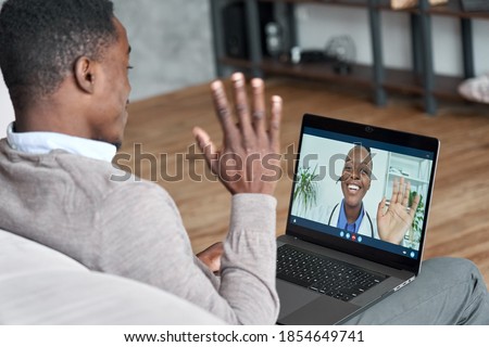 Male black patient talking on conference video call to female african doctor. Virtual therapist consulting young man during online appointment on laptop at home. Telemedicine chat, telehealth meeting