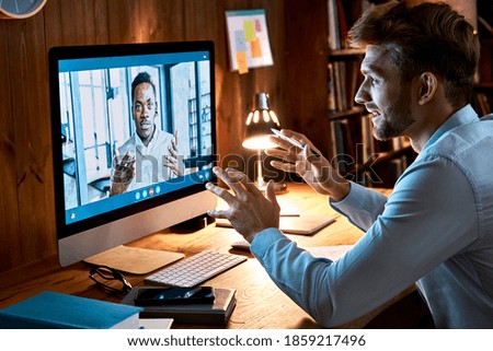 Caucasian business man talking with african male partner coach on video conference call discussing social distance work at virtual remote meeting videoconference chat using pc computer at home office.
