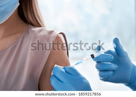Male doctor holding syringe making covid 19 vaccination injection dose in shoulder of female patient. Flu influenza vaccine clinical trials concept, corona virus treatment side effect, inoculation.  Photo stock © 