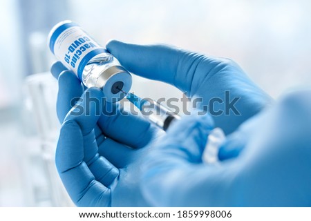 Male doctor hand wears medical glove holding syringe taking covid 19 corona virus liquid vaccine from vial bottle preparing for injections. Coronavirus immunization flu treatment vaccination concept.