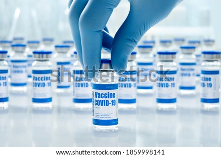 Hand of male doctor wearing medial glove holding covid 19 corona virus vaccine vial bottle for injection on medical pharmaceutical background. Coronavirus cure manufacture, flu treatment medicine drug