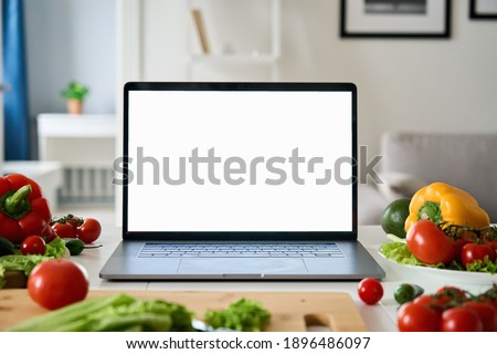 Laptop computer with mockup white screen on vegetarian healthy food vegetable background. Online grocery shopping delivery app ads concept, cook book diet plan nutrition recipes, close up view.