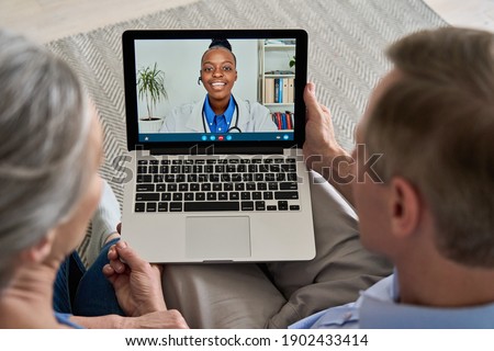 Over shoulder view of old grandparents couple patients video calling virtual doctor using laptop at home. Online telemedicine chat meeting. Seniors ehealth, telehealth consultation, tele medicine.