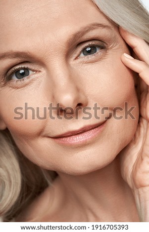 Happy attractive 50 years old middle aged mature woman touching healthy soft face skin looking at camera. Anti age dry skin care tightening treatment ads. Face close up view crop detail portrait