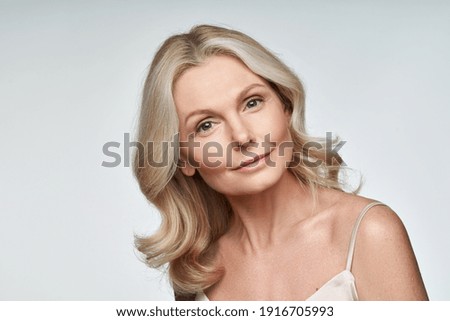 Beautiful 50s middle aged mature woman looking at camera isolated on white. Mature old lady close up portrait. Anti age healthy face skin care beauty, older skincare cosmetics, and cosmetology concept