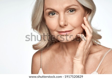 50s mid aged woman touching face skin looking at camera. Attractive mature old woman looking at camera isolated on white background advertising dry skin care treatment anti age skincare. Close up view