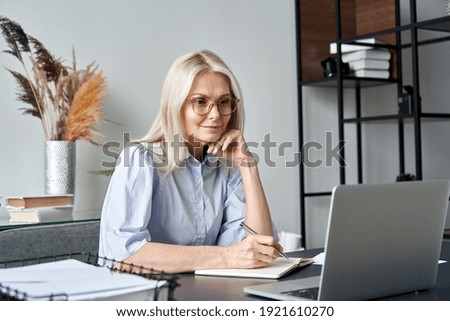 Middle aged older business woman watching professional training class, online webinar on laptop computer remote working, distance learning from home office, conference calling in virtual chat meeting.