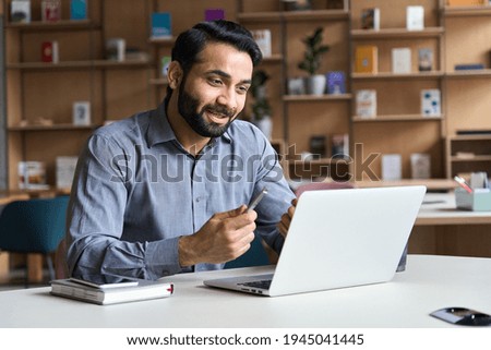 Young bearded indian business man teacher talking, teleworking, having virtual classroom meeting working on laptop computer giving online webinar training, remote class on video conference call.