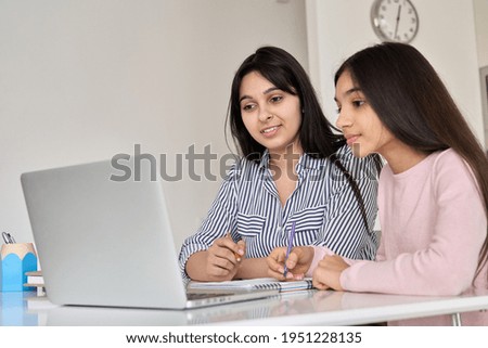 Indian mother helping teen school daughter studying online class, watching video on laptop, zoom virtual school at home. Mum and teenage child girl e learning remote lesson. Distance education.