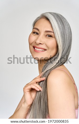 Vertical portrait of gorgeous happy joyful middle aged mature cheerful asian woman, senior older 50s gray haired lady isolated on white. Ads of aesthetic medicine spa salon hair care.
