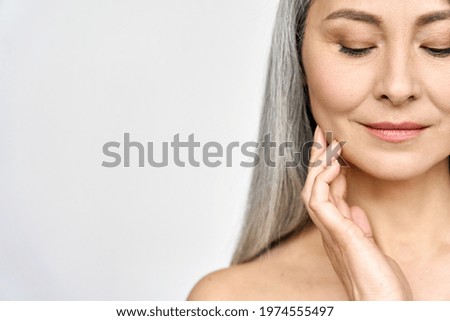 Senior older middle aged Asian woman with grey hair and radiant face with perfect skin. Advertising of rejuvenating skincare and makeup for natural radiant glow and healthy skin. Copy space.