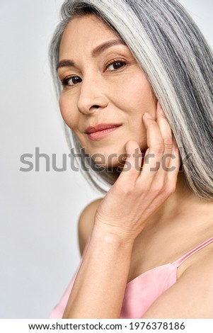Vertical portrait of gorgeous happy middle aged mature asian woman, senior older 50 year lady looking at camera touching her face isolated on white. Ads of lifting anti wrinkle skin care, spa.