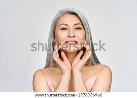 Portrait of gorgeous beautiful middle aged mature asian woman, senior older 50 year lady looking at camera touching her face isolated on white. Ads of lifting anti wrinkle skin care, spa.
