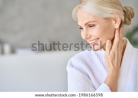Headshot of happy smiling gorgeous middle aged woman in white bathrobe at spa salon hotel looking away. Advertising of bodycare spa procedures antiage recreation treatment concept.