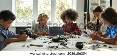 Multiracial school kids students making robotic cars using tablet computer. Diverse junior children pupils building robot vehicle learning at table at STEM code ai engineering science education class. Stockfoto © 