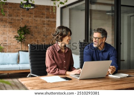 Similar – Image, Stock Photo Two business people discussing financial data looking at computer screen. Businesswoman talking to young male coworker in office. People entrepreneurs having conversation working together