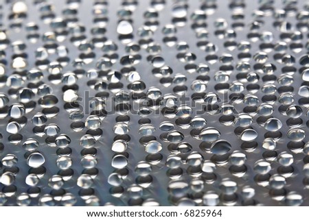Extreme Close-up of water droplets over grayish reflective background. Shallow D.O.F. Portrait Orientation.