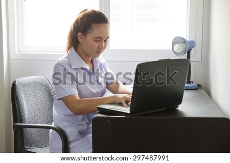 Asian nurse working in office near window on desk