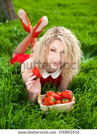 A beautiful young woman, a blonde with a basket of strawberries. Spring, bright green grass. A series of photos in my portfolio