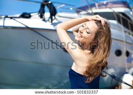 Young beautiful brunette woman relaxing on the dock near the boat on a sunny day in summer.