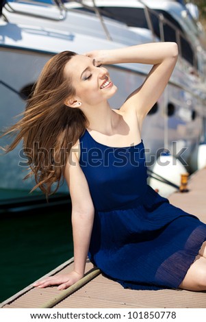 Young beautiful brunette woman relaxing on the dock near the boat on a sunny day in spring.