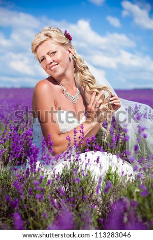 Young and beautiful bride in love, wedding day in summer. Enjoy a moment of happiness and love in a lavender field. In a luxurious wedding dress on a background bright blue sky with clouds.